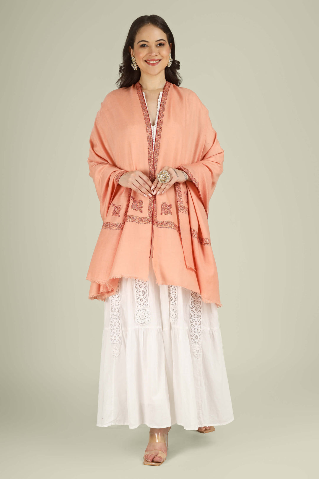 This Peach GI Kashmiri Pure Pashmina Raiha Hashidaar Shawl comes in a soft peach base highlighted with a geometric hashidaar border and a single ornate corner motif, giving a clean, modern look with a touch of traditional detail.
