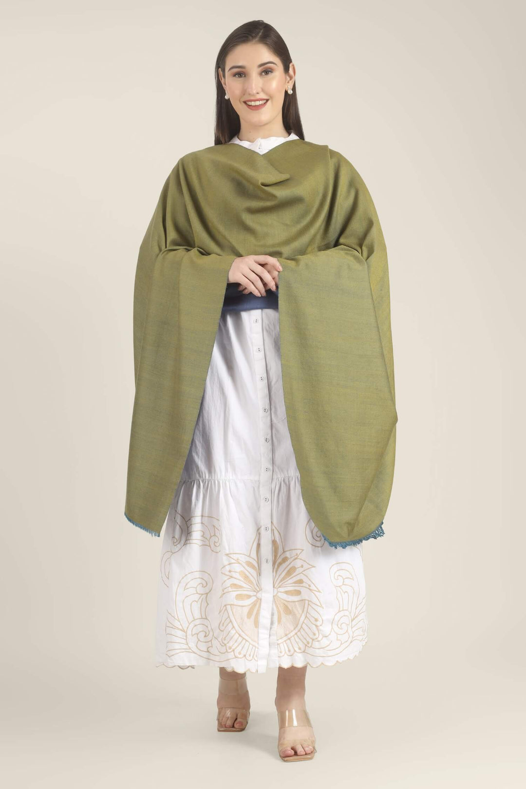 Model wearing a blue and olive-green reversible Pure Kashmiri Pashmina shawl with teal fringe over a white embroidered dress.