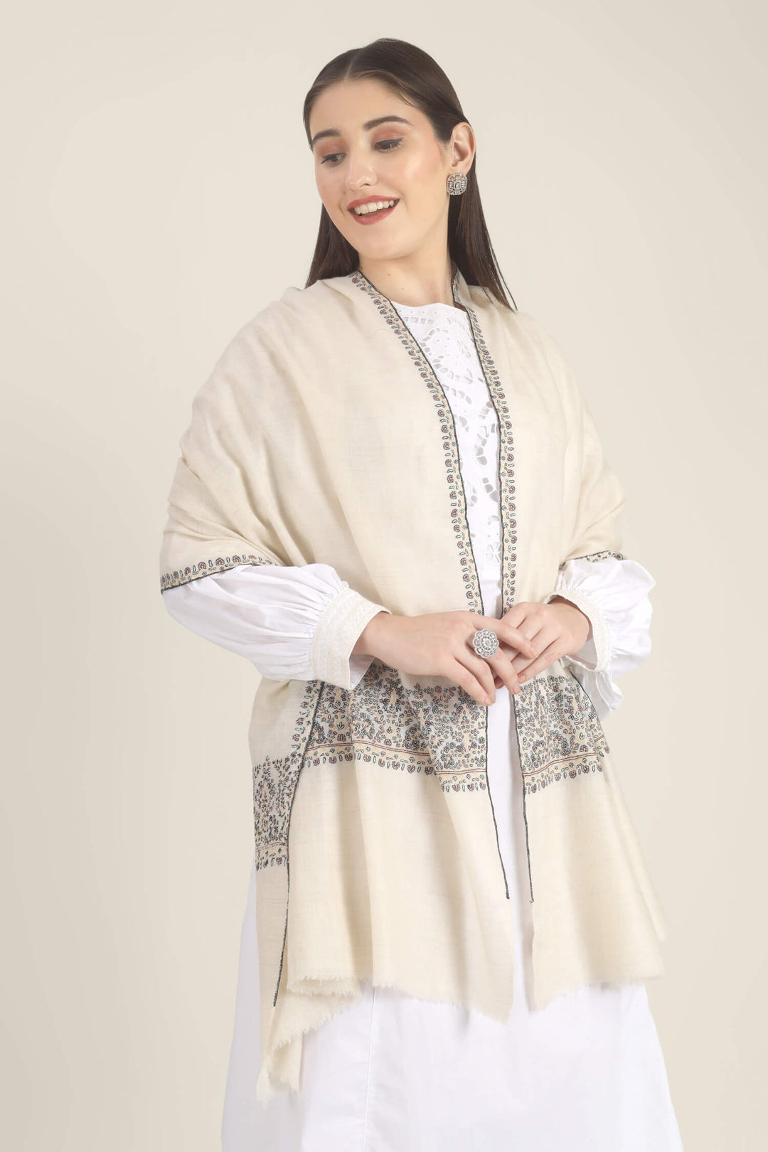 Model wearing a white GI Kashmiri Pure Pashmina stole with multicolour floral Sozni embroidered borders over a white outfit.