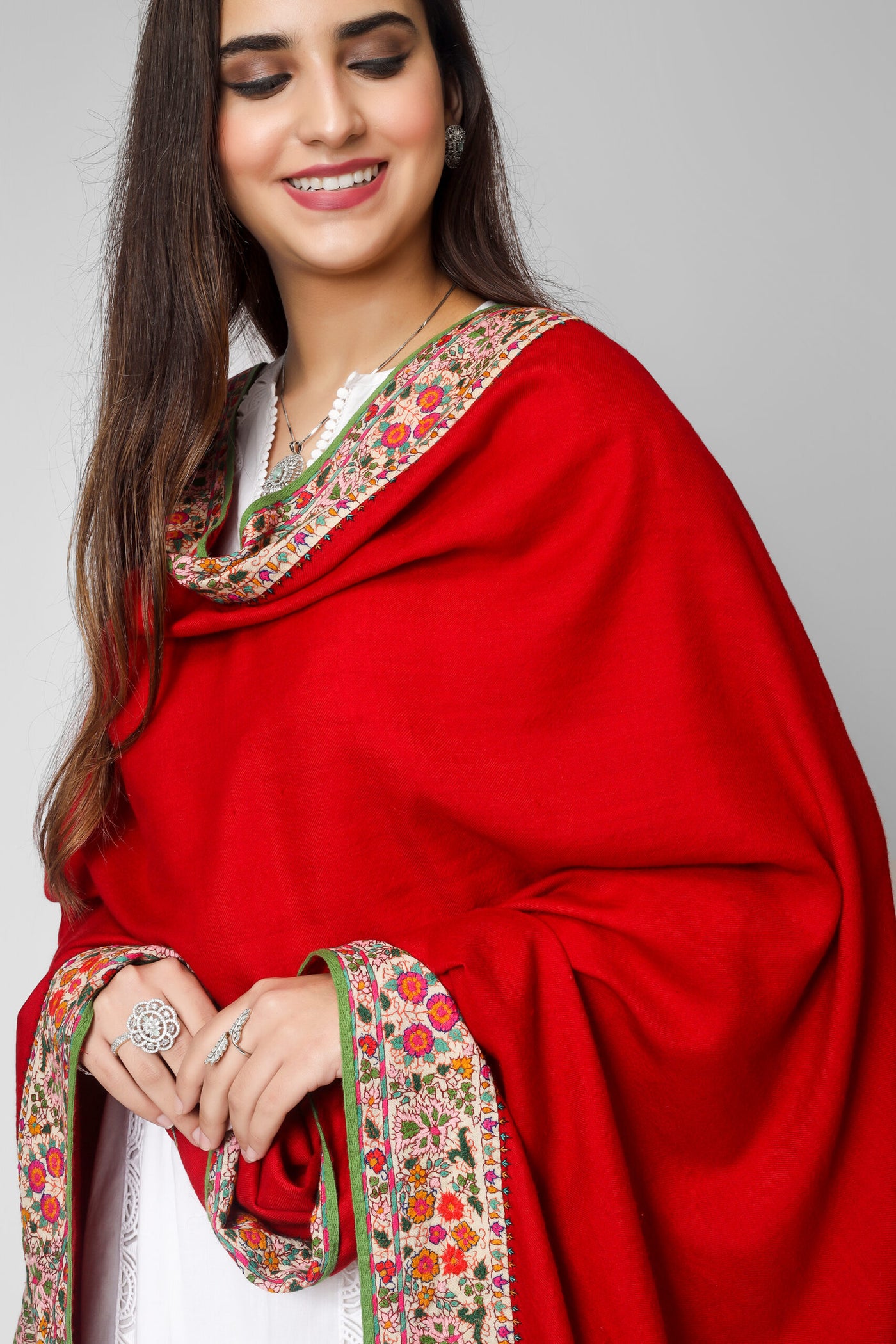  Kashmiri pashmina shawl, you may swaddle yourself in luxury. It was produced from the best pashmina wool and it has exquisite stitching and a lovely crimson Doordaar design. The borders are covered in a  Sozni patchwork embroidery border that displays beautiful designs created from tangled multicolor Sozni threads. 